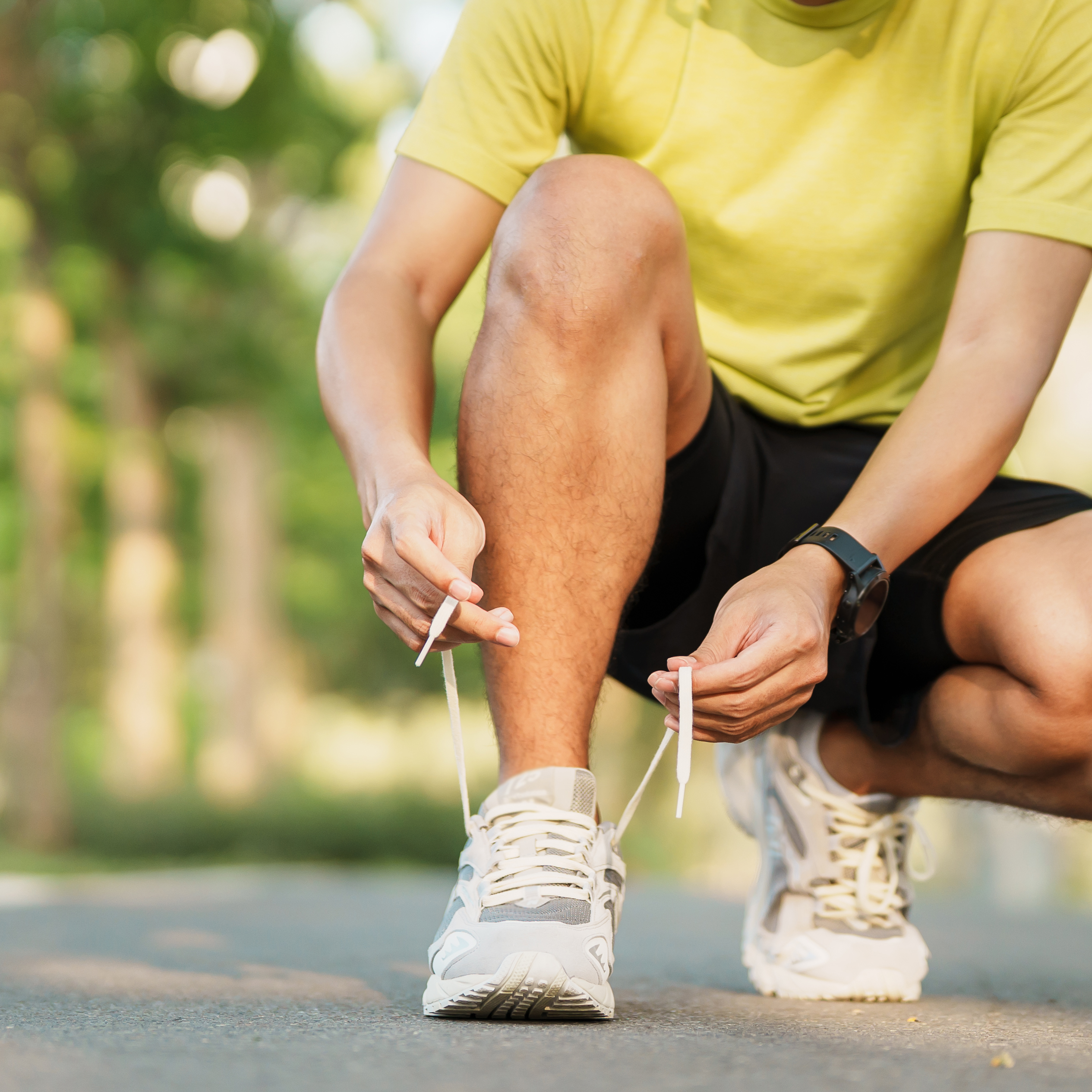 Young athlete man tying running shoes in the park outdoor Young athlete man tying running shoes in the park outdoor